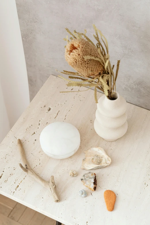 a white vase sitting on top of a wooden table, a marble sculpture, by Anna Boch, trending on unsplash, lacey accessories, white rocks made of bone, skincare, in a white boho style studio