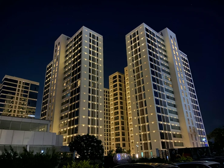 a group of tall buildings lit up at night, bauhaus, ivory towers, real estate photography, 3 - piece, manila