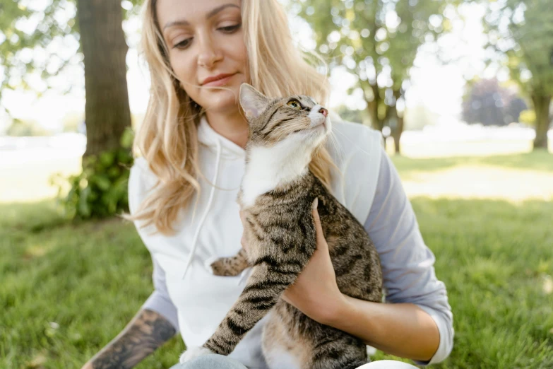 a woman sitting in the grass holding a cat, trending on pexels, avatar image, white, high resolution image, body shot