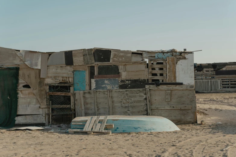 a group of shacks sitting on top of a sandy beach, unsplash, arte povera, background image, boarded up, aida muluneh, an film still