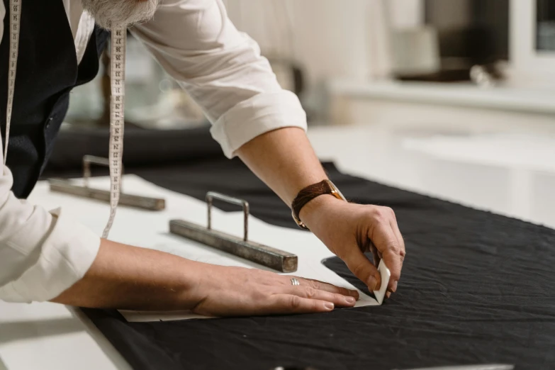 a person cutting a piece of fabric on a table, unsplash, elegantly dressed, creterion collection, olivia kemp, architect