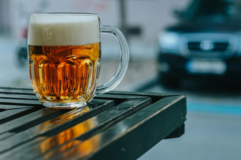 a glass of beer sitting on top of a wooden table, on a parking lot, thumbnail, fan favorite, buying beers in the british bar