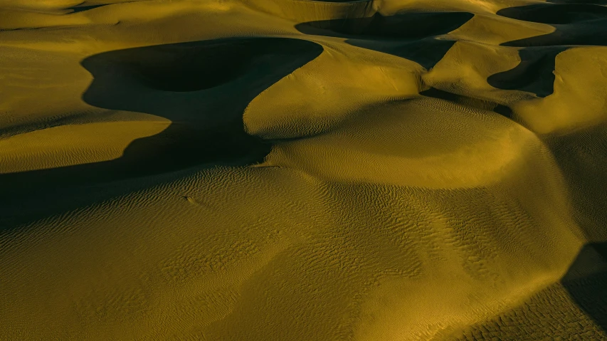 a person riding a surfboard on top of a sandy beach, by Filip Hodas, unsplash contest winner, land art, black and yellow colors, craters, folds, crisp contour lines