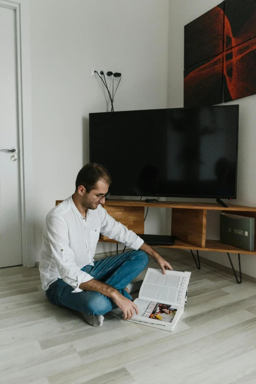 a man sitting on the floor reading a newspaper, a cartoon, by Adam Marczyński, pexels contest winner, hotel room, tv frame, handsome male, high resolution photo