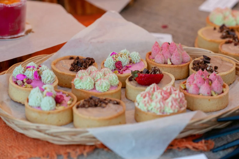 a tray of desserts sitting on top of a table, a pastel, by Lee Loughridge, pexels, festivals, local close up, fairy circles, market