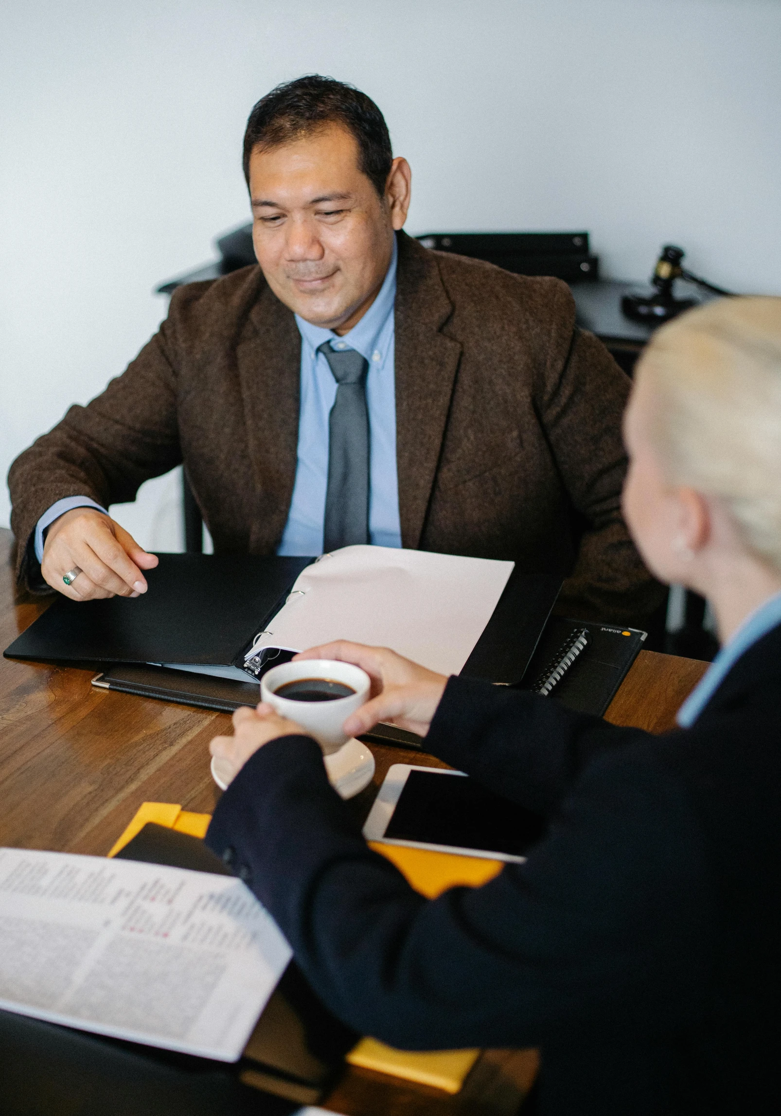 a couple of people that are sitting at a table, wearing a business suit, sitting on a mocha-colored table, in meeting together, thumbnail