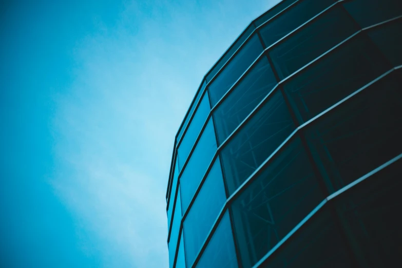 a tall glass building with a blue sky in the background, a picture, pexels contest winner, rounded shapes, dark building, half turned around, thumbnail