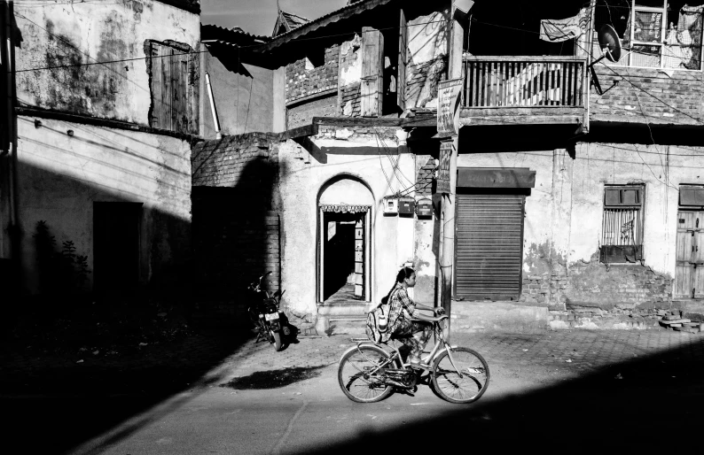 a black and white photo of a person on a bike, by Sudip Roy, pexels contest winner, dilapidated houses, sunny light, dreamy chinese town, shot on hasselblad