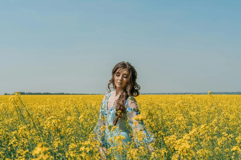 a woman standing in a field of yellow flowers, inspired by Elsa Bleda, pexels contest winner, in blue and yellow clothes, girl with brown hair, various posed, full body image