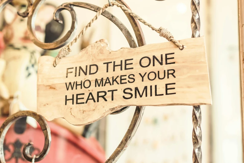 a sign that says find the one who makes your heart smile, by Arabella Rankin, as photograph, wooden decoration, smiling mouth, intricate image