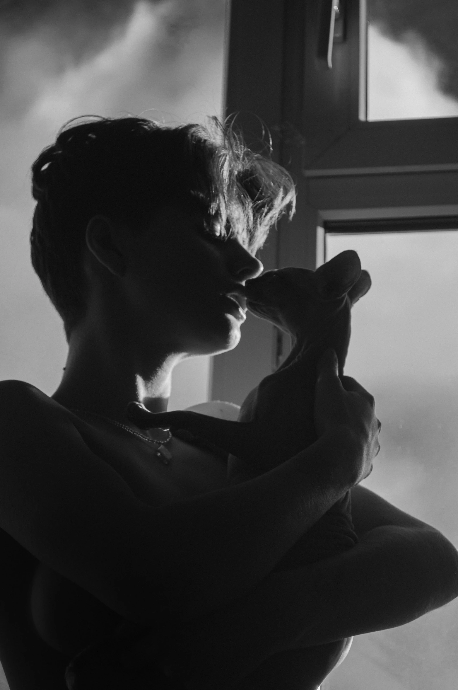 a woman holding a teddy bear in front of a window, a black and white photo, by Alexis Grimou, pexels contest winner, realism, making out, androgyny, woman silhouette, soft light.4k