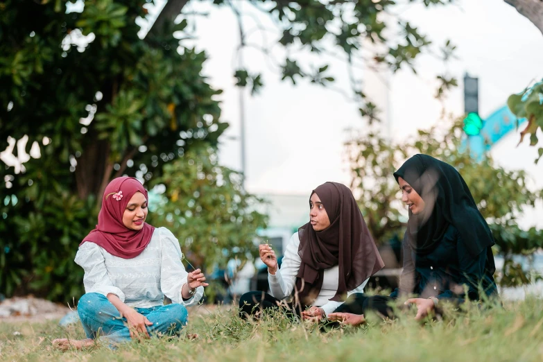 a group of women sitting on top of a lush green field, a picture, by Ismail Acar, shutterstock, hurufiyya, in a city park, avatar image, malaysian, people on a picnic