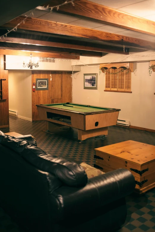 a living room filled with furniture and a pool table, in a basement, chalet, quebec, office/thrift store/social hall