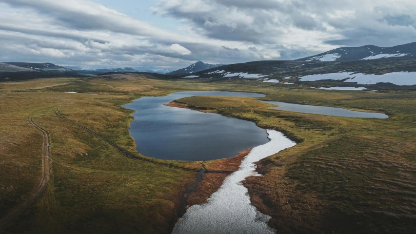 a large body of water sitting on top of a lush green field, by Jesper Knudsen, pexels contest winner, land art, desolate arctic landscape, blue river in the middle, unsplash photo contest winner, autumn