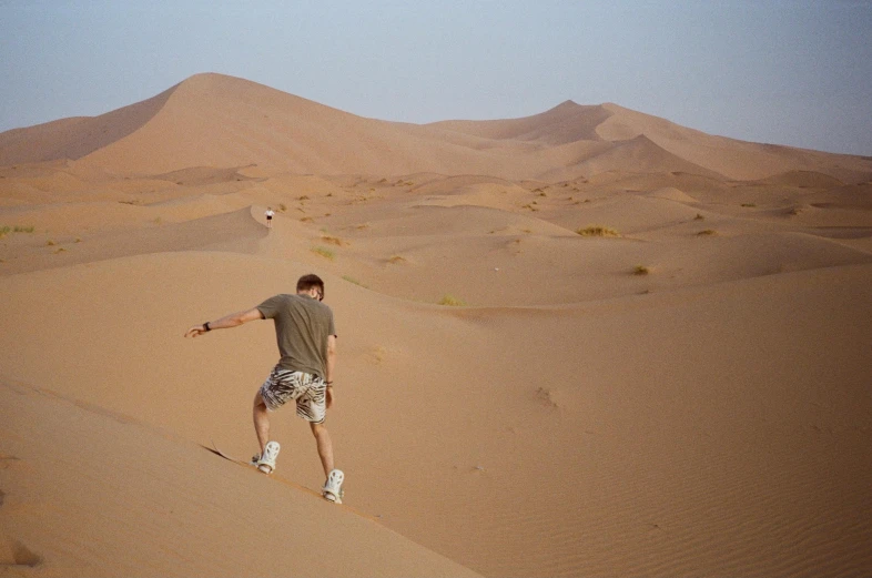 a man riding a skateboard in the middle of a desert, inspired by Steve McCurry, arabesque, sand banks, trecking, doing a kick, sickly