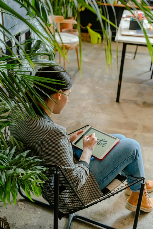 a woman sitting in a chair reading a book, a cartoon, pexels contest winner, draw with wacom tablet, big interior plants, high angle shot, sustainable materials