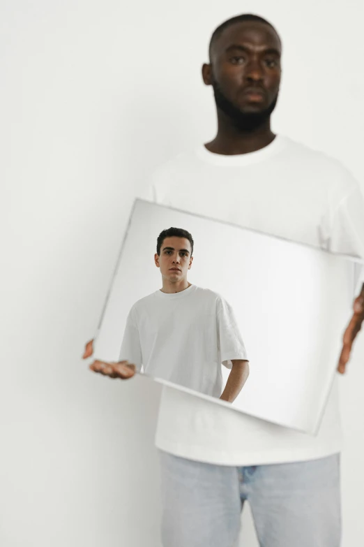 a man holding a picture of himself in a mirror, inspired by Carlos Berlanga, pexels contest winner, plain white tshirt, studio shoot, pete davidson, large format photograph