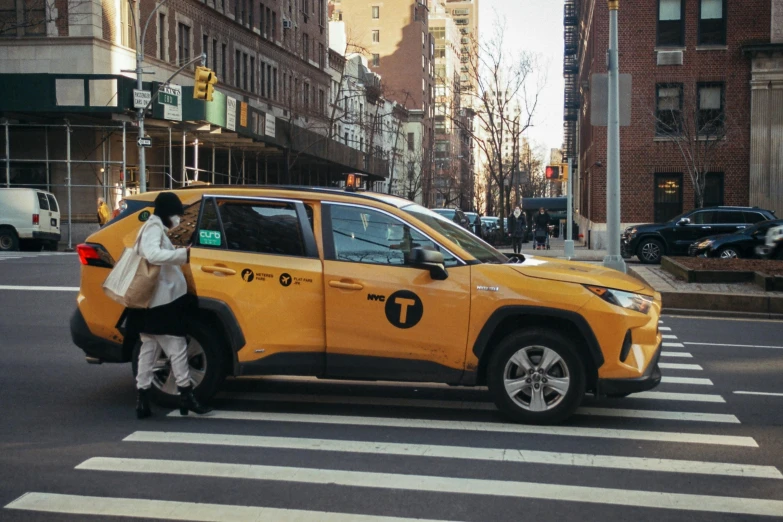 a woman standing next to a yellow car on a city street, pexels contest winner, happening, attacking nyc, accompanying hybrid, 🦩🪐🐞👩🏻🦳, square