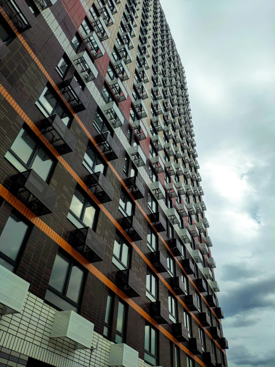 a very tall building with lots of windows, by Washington Allston, unsplash, modernism, dark grey and orange colours, crenellated balconies, slide show, new york buildings