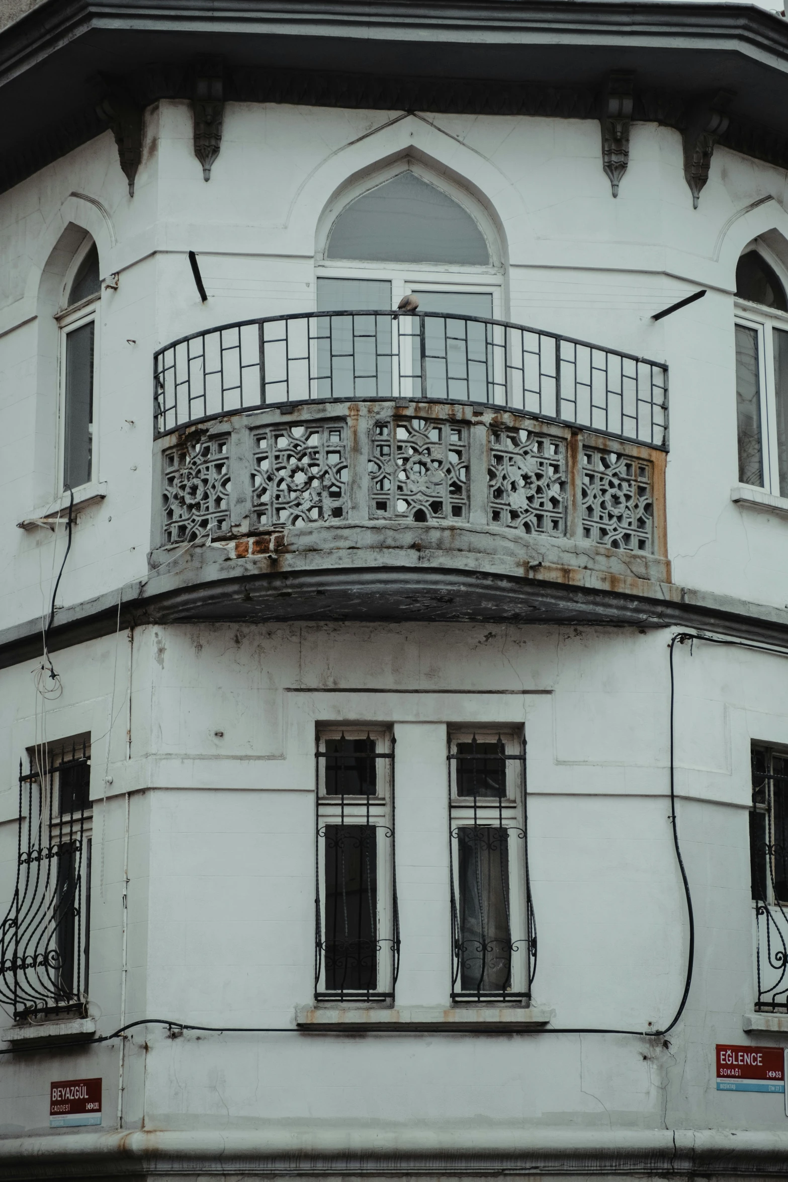 a tall white building sitting on the side of a street, pexels contest winner, art nouveau, iron railing, old abandoned house, middle eastern details, bay window