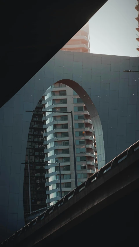 a view of a tall building through a window, a picture, inspired by Zha Shibiao, pexels contest winner, modernism, vintage footage on tokyo streets, curving geometric arches, fujicolor photo, cinematic. by leng jun