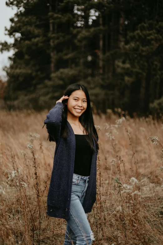 a woman standing in a field of tall grass, pexels contest winner, young asian girl, wearing a cardigan, avatar image, college