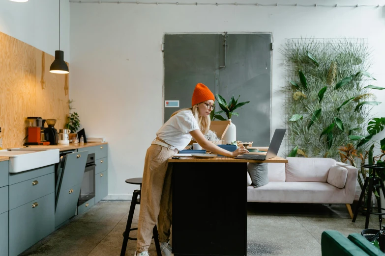 a woman sitting at a table working on a laptop, by Emma Andijewska, big interior plants, wearing white chef hat, great space, profile image