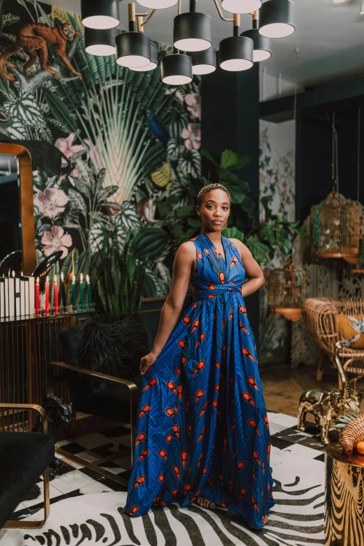 a woman in a blue dress standing in a living room, by Ella Guru, maximalism, standing in a restaurant, wearing an african dress, wearing a dress made of vines, official store photo
