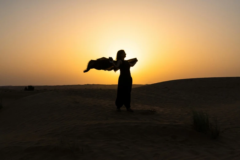 a person holding a kite in the desert, an album cover, pexels contest winner, arabesque, woman silhouette, arabian nights, praising the sun, belly dancing