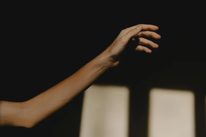 a close up of a person's hand reaching out of a window, by Emma Andijewska, trending on pexels, light and space, in a pitch black room, dancing elegantly over you, slightly tanned, light falling on face