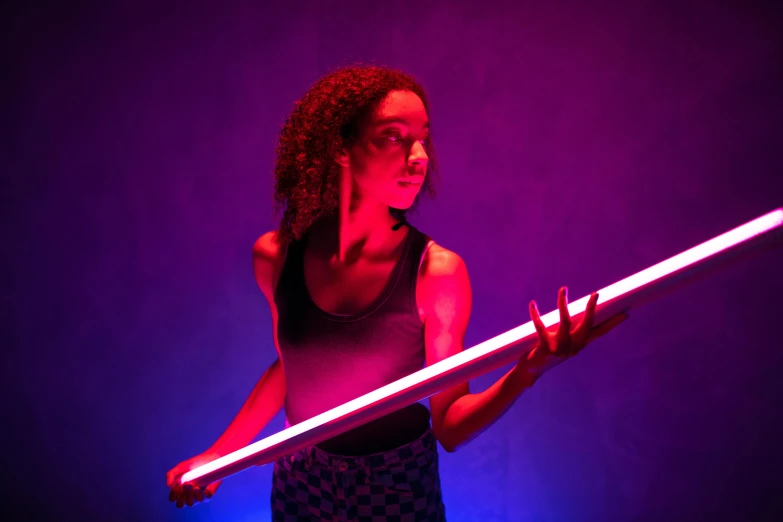 a woman holding a light saber in front of a purple background, by Niels Lergaard, unsplash, kinetic art, dan flavin, red and blue lighting, ashteroth, holding a giant weapon