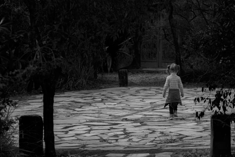 a black and white photo of a woman walking down a path, a black and white photo, by Ivana Kobilca, pixabay, little boy, boy and girl, walking at the garden, nightmare