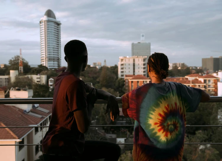 a couple of people sitting on top of a balcony, unsplash, hurufiyya, tie die shirt, very kenyan, gradins view, back towards camera