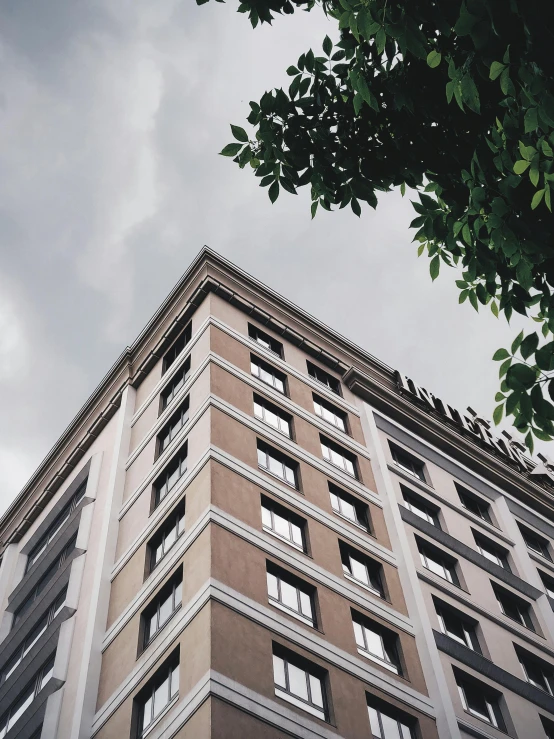 a tall building with lots of windows under a cloudy sky, inspired by Cheng Jiasui, unsplash, neoclassicism, south jakarta, low quality photo, trees outside, ansel ]