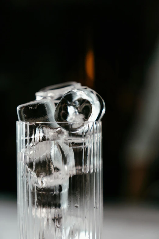 a glass filled with ice sitting on top of a table, unsplash, purism, silver small small small glasses, profile, speakeasy, long shot from back