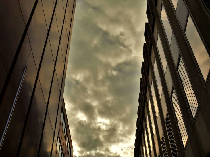 a couple of tall buildings next to each other, a picture, flickr, dramatic sky, sky made of ceiling panels, brooding clouds', narrow