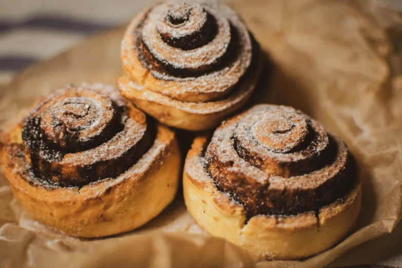 three pastries sitting on top of a piece of paper, by Emma Andijewska, trending on pexels, rosette, 6 pack, spiral, brown hair in two buns