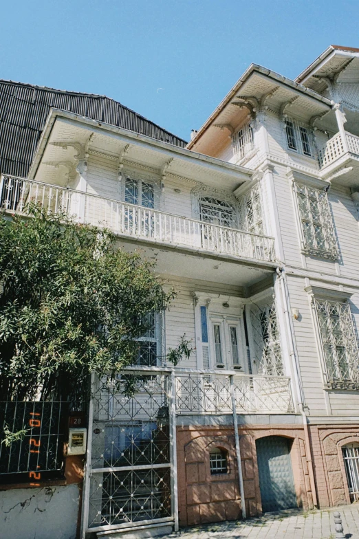 a tall white building sitting on the side of a road, inspired by Francisco Zúñiga, art nouveau, wooden house, istanbul, 1990s photograph, balcony