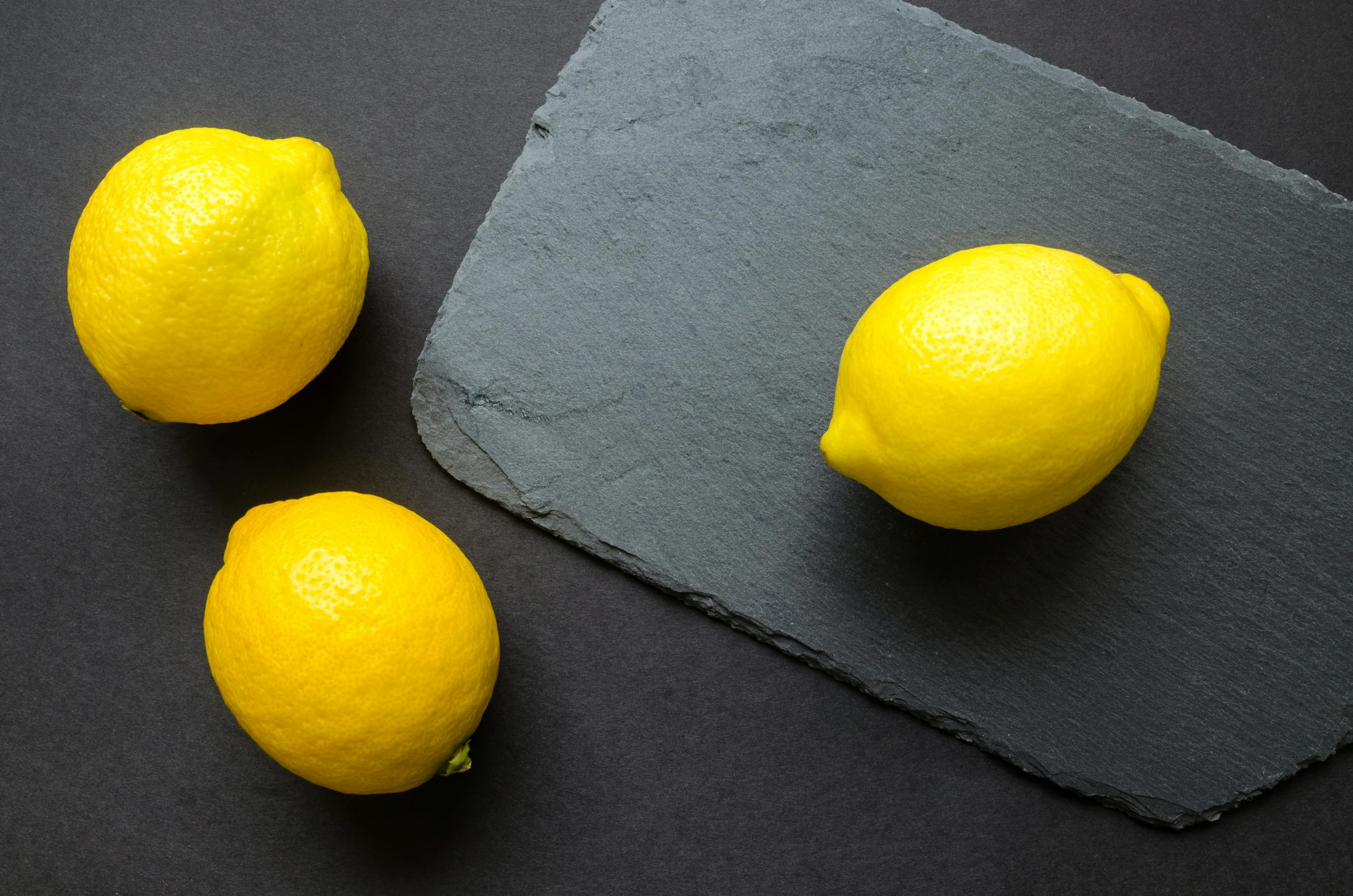 a couple of lemons sitting on top of a cutting board, slate, background image, laura watson, trending photo