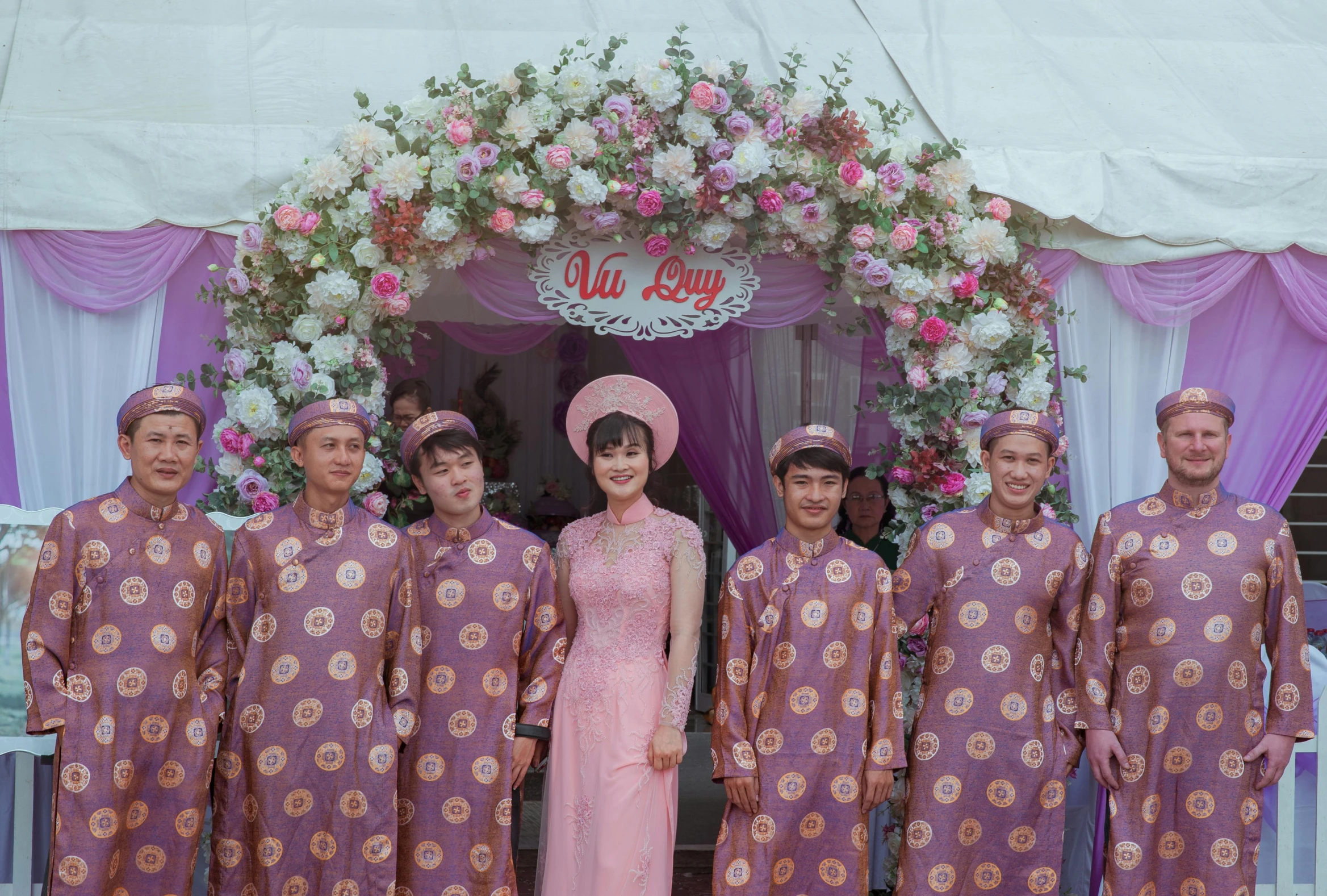 a group of people standing next to each other, a colorized photo, inspired by Cui Bai, pexels, happening, ao dai, pink arches, bouquet, 15081959 21121991 01012000 4k