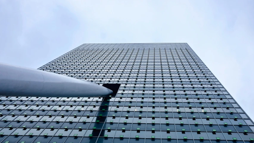 a tall building with lots of windows next to a street light, inspired by Zaha Hadid, pexels contest winner, canary wharf, turbines, tail fin, photo taken from the ground