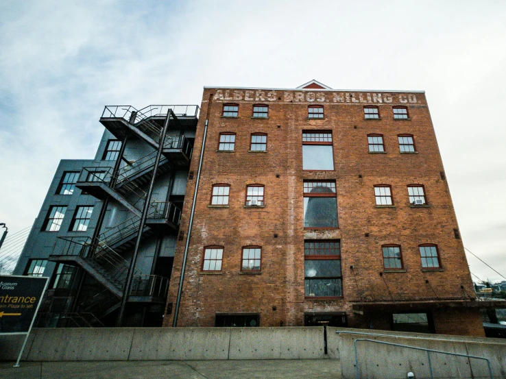 a tall brick building sitting next to a parking lot, pexels contest winner, process art, mill, external staircases, yeg, seen from outside