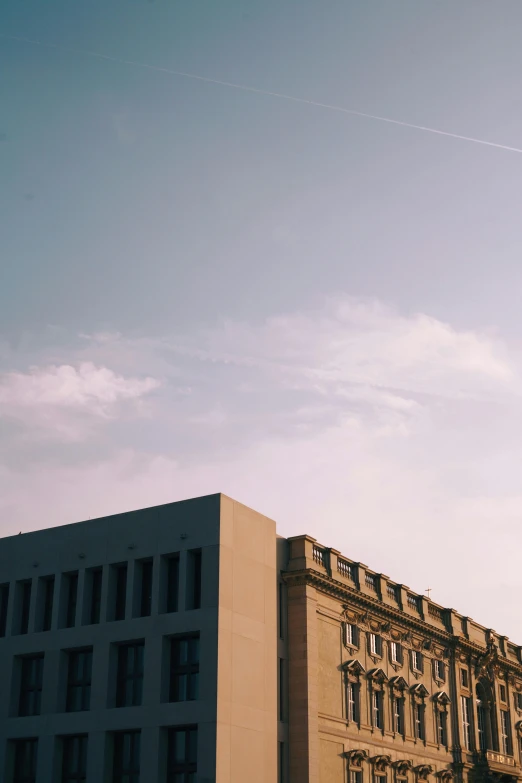 a large building with a clock tower in front of it, a photo, trending on unsplash, brutalism, sky gradient, berlin city, low quality photo, side view from afar