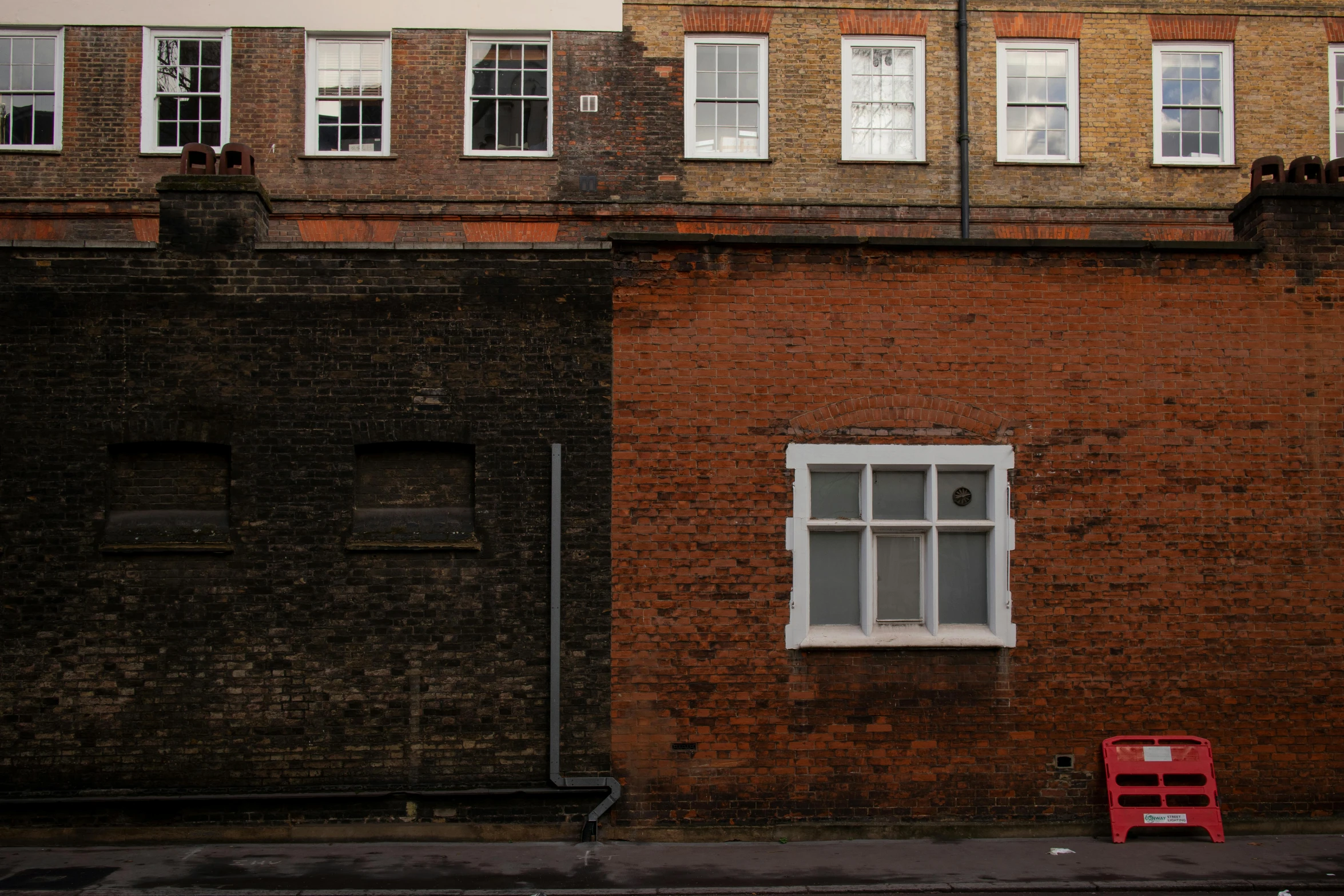 a red chair sitting in front of a brick building, inspired by Thomas Struth, pexels contest winner, london architecture, street elevation, a small, ignant