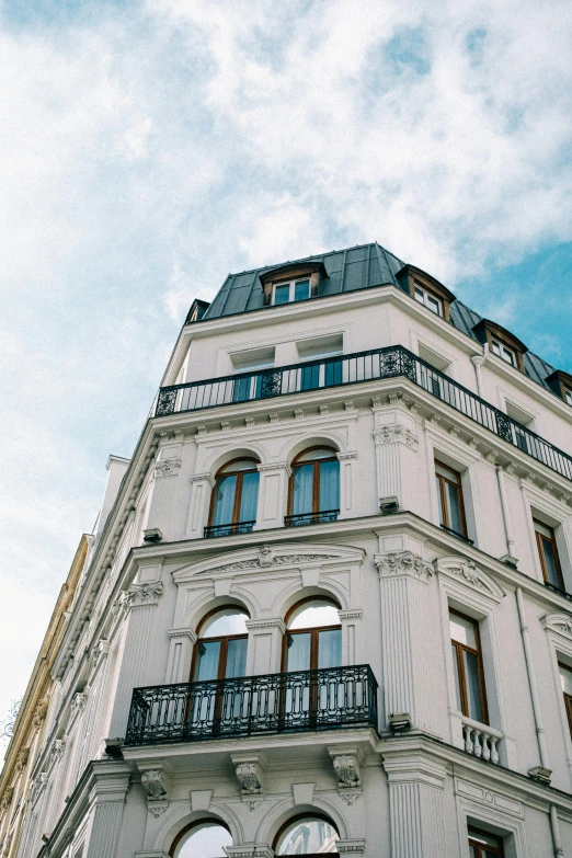 a tall white building with many windows and balconies, inspired by Albert Paris Gütersloh, unsplash, art nouveau, clear blue skies, exterior shot, blond, rooftop