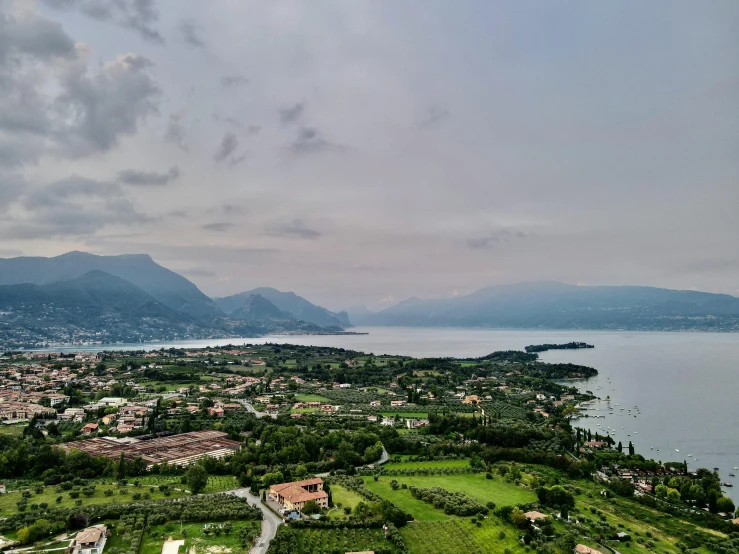 a large body of water next to a lush green hillside, by Alessandro Allori, pexels contest winner, drone view of a city, lakeside mountains, boka, aerial view of an ancient land