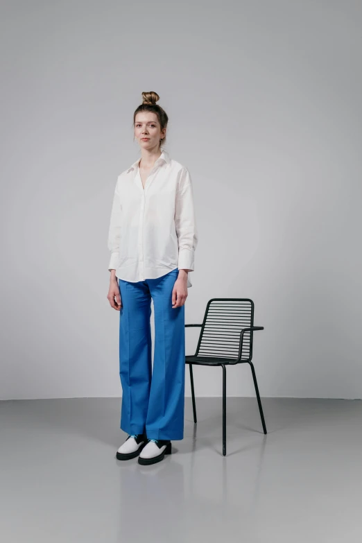 a woman standing next to a chair in a room, by Vadym Meller, wearing a linen shirt, blue pants, thumbnail, flowy