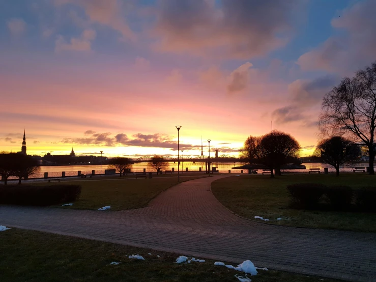 a walkway in a park next to a body of water, by Jan Tengnagel, pexels contest winner, happening, cold sunset, bright sky, seaview, annato finnstark