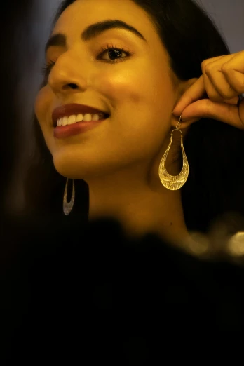 a close up of a person wearing a pair of earrings, an album cover, pexels contest winner, platinum jewellery, light smiling, india, (night)