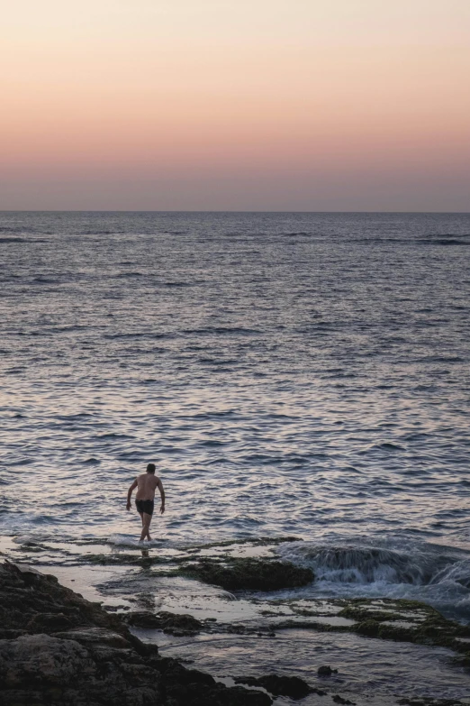 a man standing in the ocean at sunset, by Elsa Bleda, australian tonalism, bondi beach in the background, stepping stones, a single, people swimming